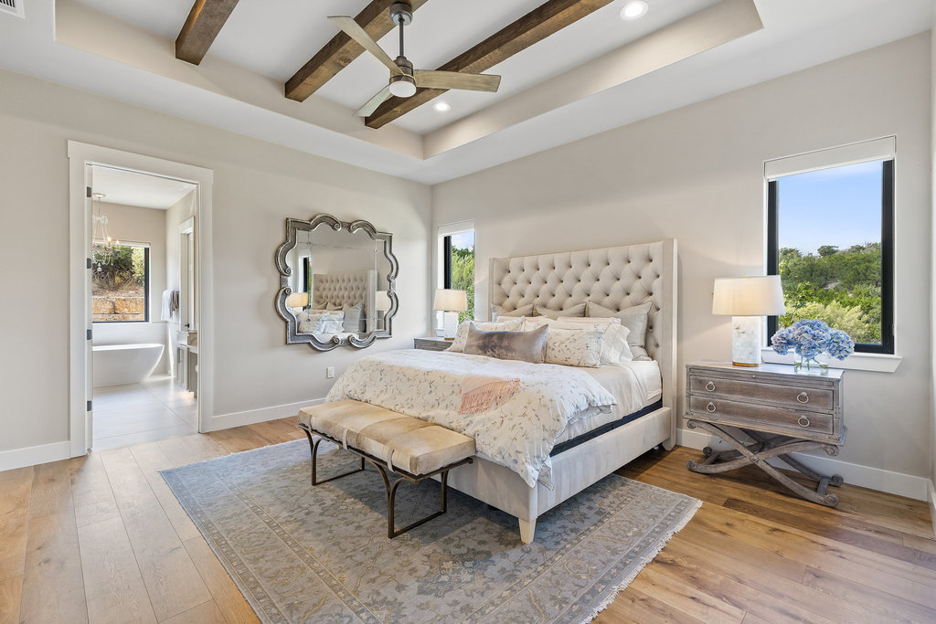 4746 R O Drive Spicewood, TX 78669 - Photo 22 of 40 a spacious bedroom with a bed a table and painting on the wall