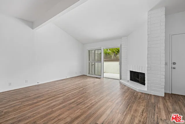 an empty room with wooden floor fireplace and windows