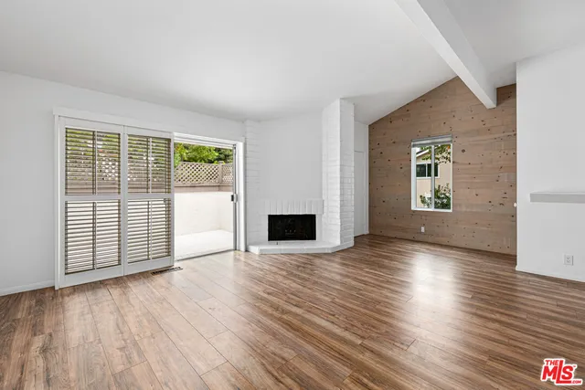 an empty room with wooden floor and a fireplace