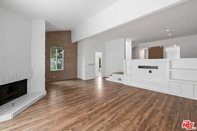 a view of a livingroom with wooden floor and a fireplace