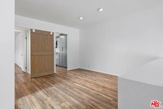 a view of an empty room with wooden floor and closet