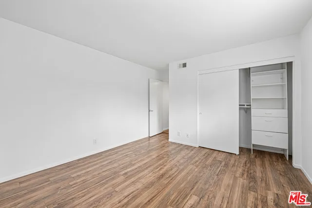 a view of an empty room with closet and a window