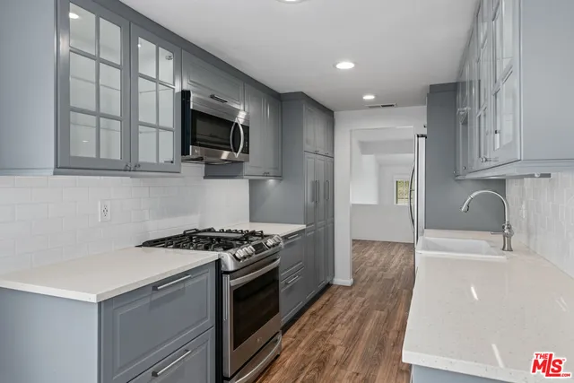 a kitchen with stainless steel appliances granite countertop a stove a sink and a microwave