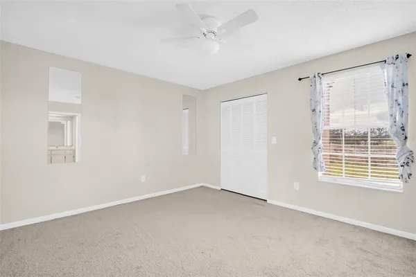 an empty room with a ceiling fan and carpet