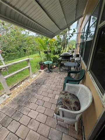 a view of backyard with table and chairs potted plants and large tree