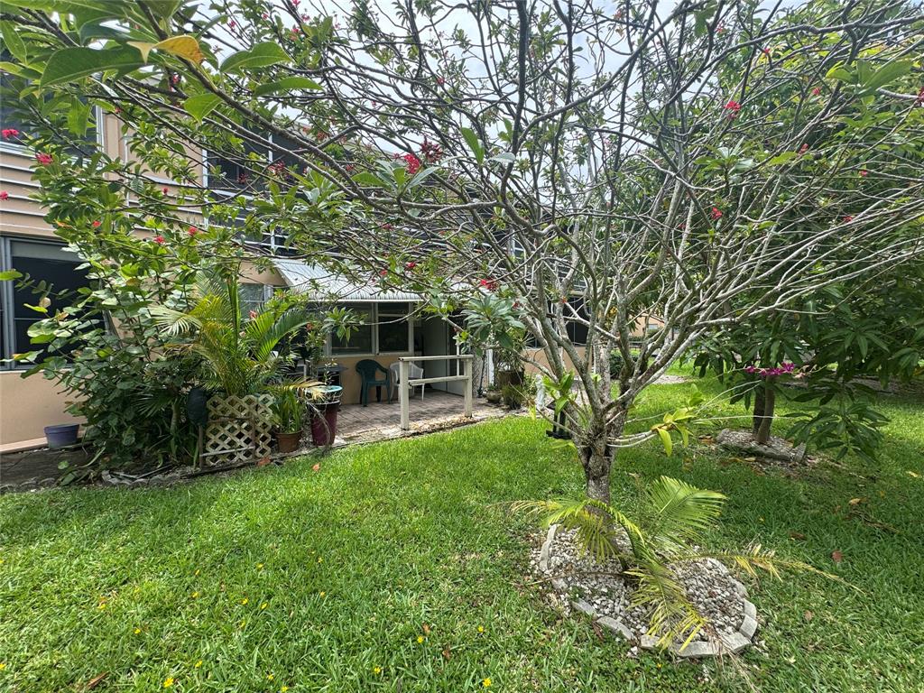61 Camden C, Unit C West Palm Beach, FL 33417 - Photo 19 of 23 a view of backyard with table and chairs potted plants and large tree