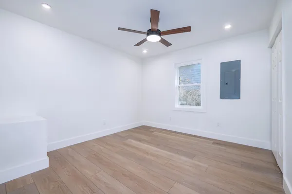 an empty room with wooden floor ceiling fan and windows