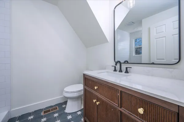 a bathroom with a granite countertop sink a toilet and a mirror