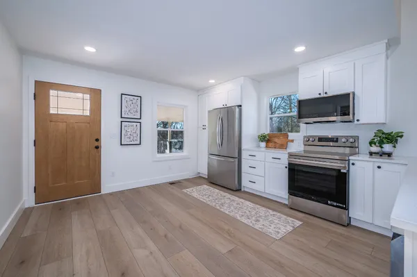 a kitchen with stainless steel appliances a stove a microwave and white cabinets