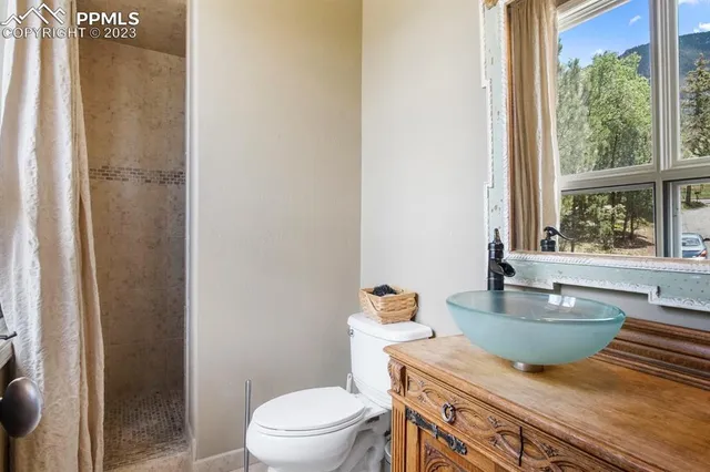 a bathroom with a granite countertop sink a toilet a mirror and shower
