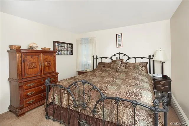 a bedroom with a bed and dresser with wooden floor
