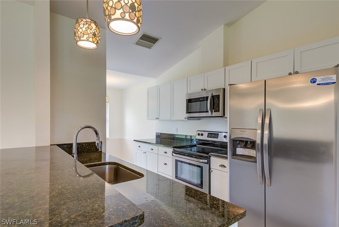 7232 Coolidge Road Fort Myers, FL 33967 - Photo 4 of 25 a kitchen with granite countertop a refrigerator and a stove top oven