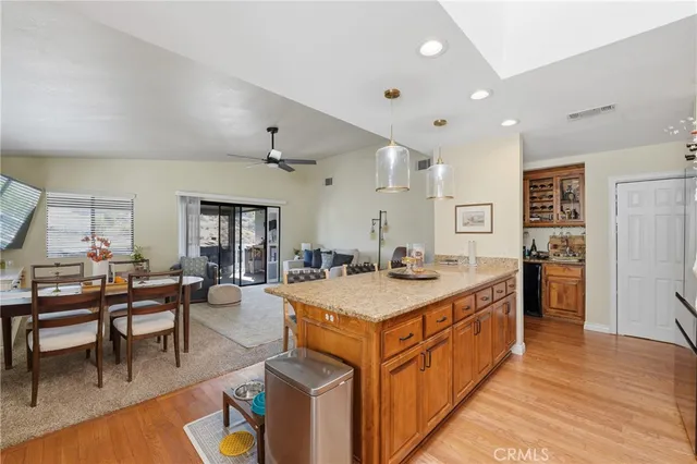 a large dining hall with stainless steel appliances granite countertop a table chairs and a refrigerator