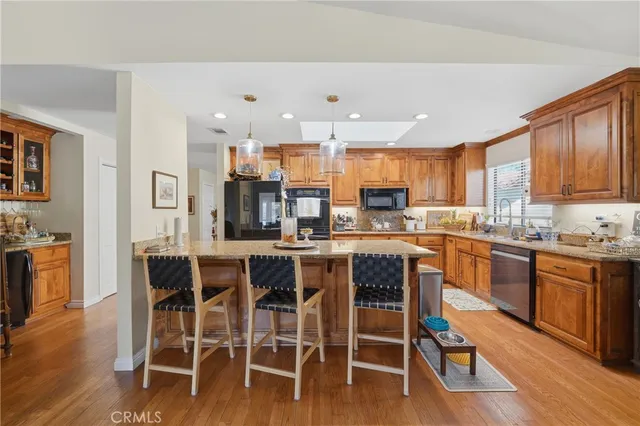 a kitchen with stainless steel appliances granite countertop wooden floor a dining table and chairs