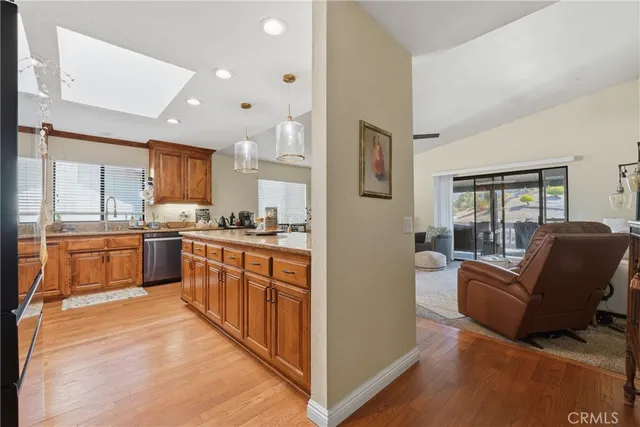 a kitchen with stainless steel appliances granite countertop a refrigerator a sink dishwasher a dining table and chairs with wooden floor