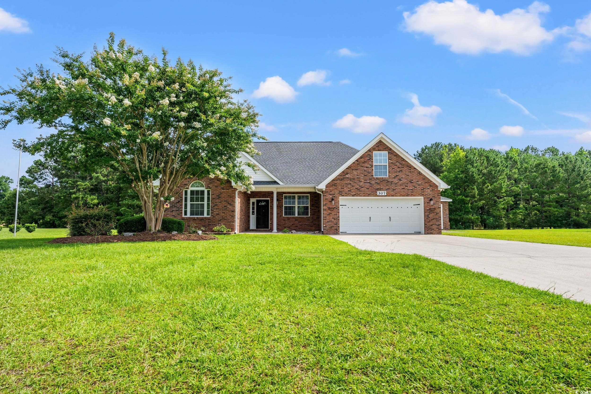 View of front of house with concrete driveway, a front lawn, and a garage