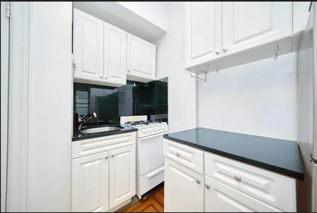 a kitchen with granite countertop white cabinets and white appliances