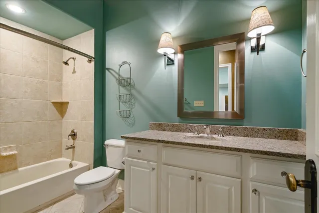 a bathroom with a granite countertop sink toilet mirror and bathtub