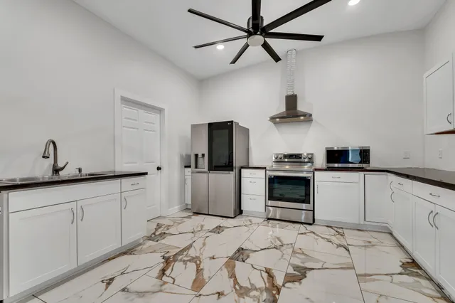 a kitchen with granite countertop white cabinets and stainless steel appliances