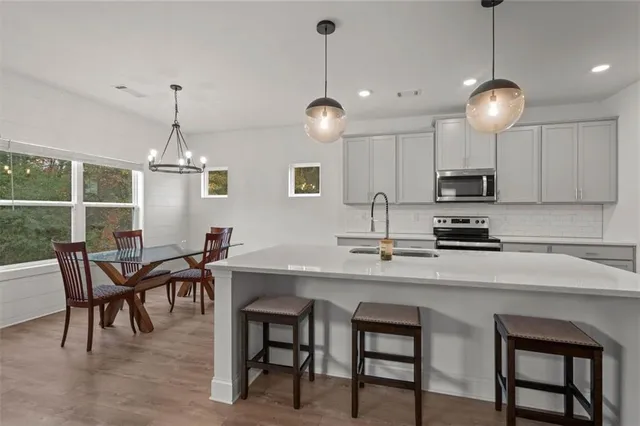 a kitchen with stainless steel appliances granite countertop a dining table chairs and white cabinets