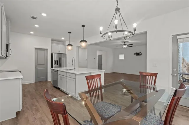 a kitchen with a dining table chairs stainless steel appliances and cabinets