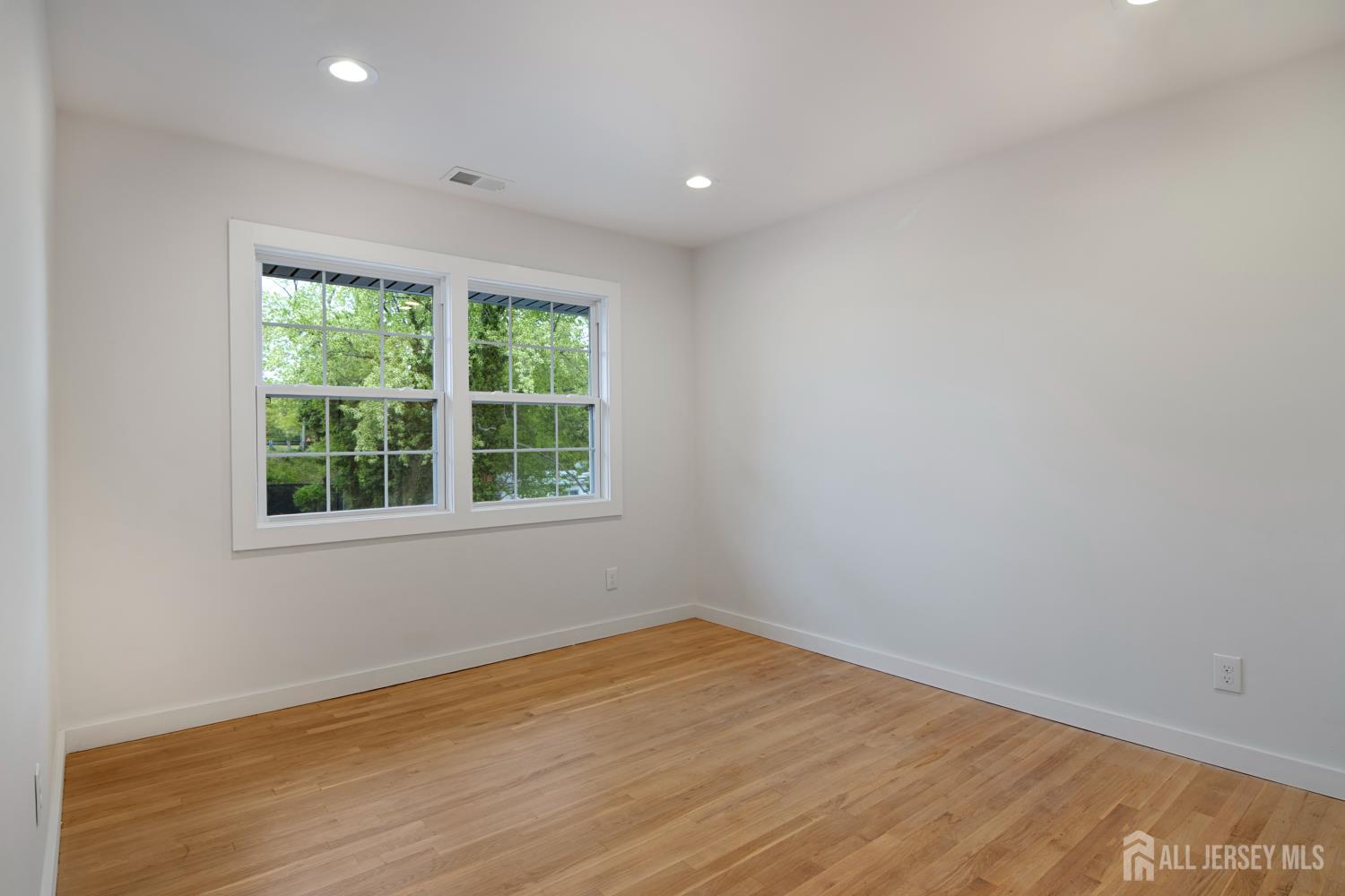 4 Morris Avenue, Unit 2A Edison, NJ 08837 - Photo 16 of 27 an empty room with wooden floor and windows