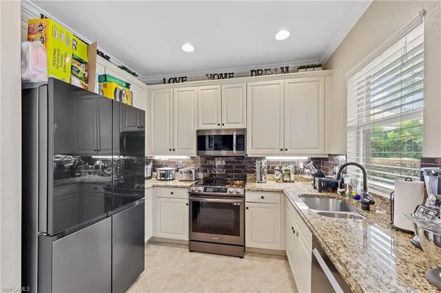 a kitchen with stainless steel appliances granite countertop a refrigerator a stove a sink and a microwave