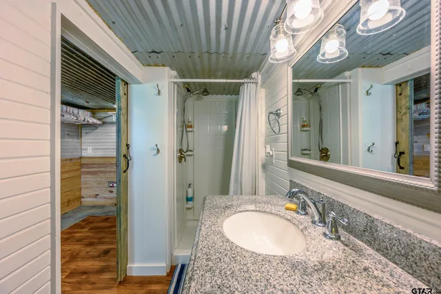 a bathroom with a granite countertop sink a mirror and shower