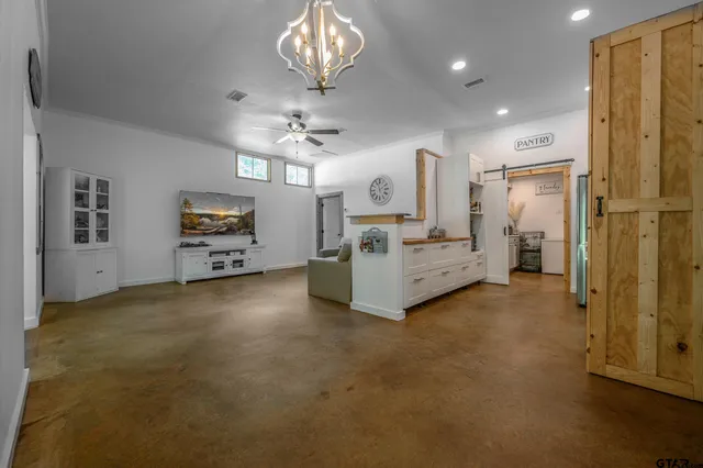 a view of a livingroom with furniture cabinet a chandelier and windows