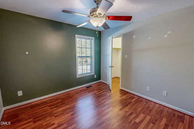a view of an empty room with window and wooden floor