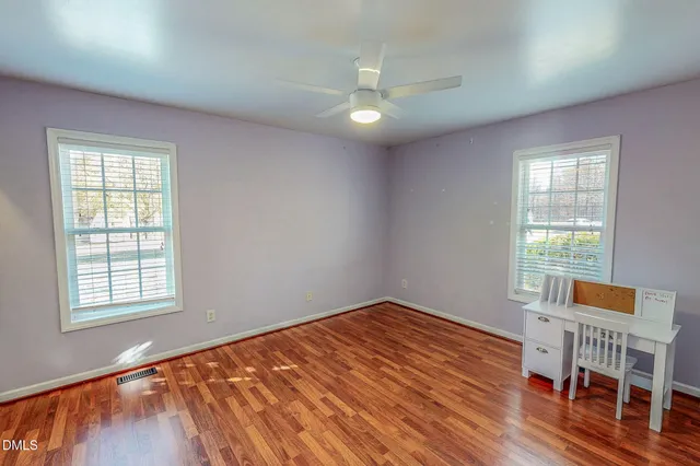 an empty room with wooden floor cabinet and windows
