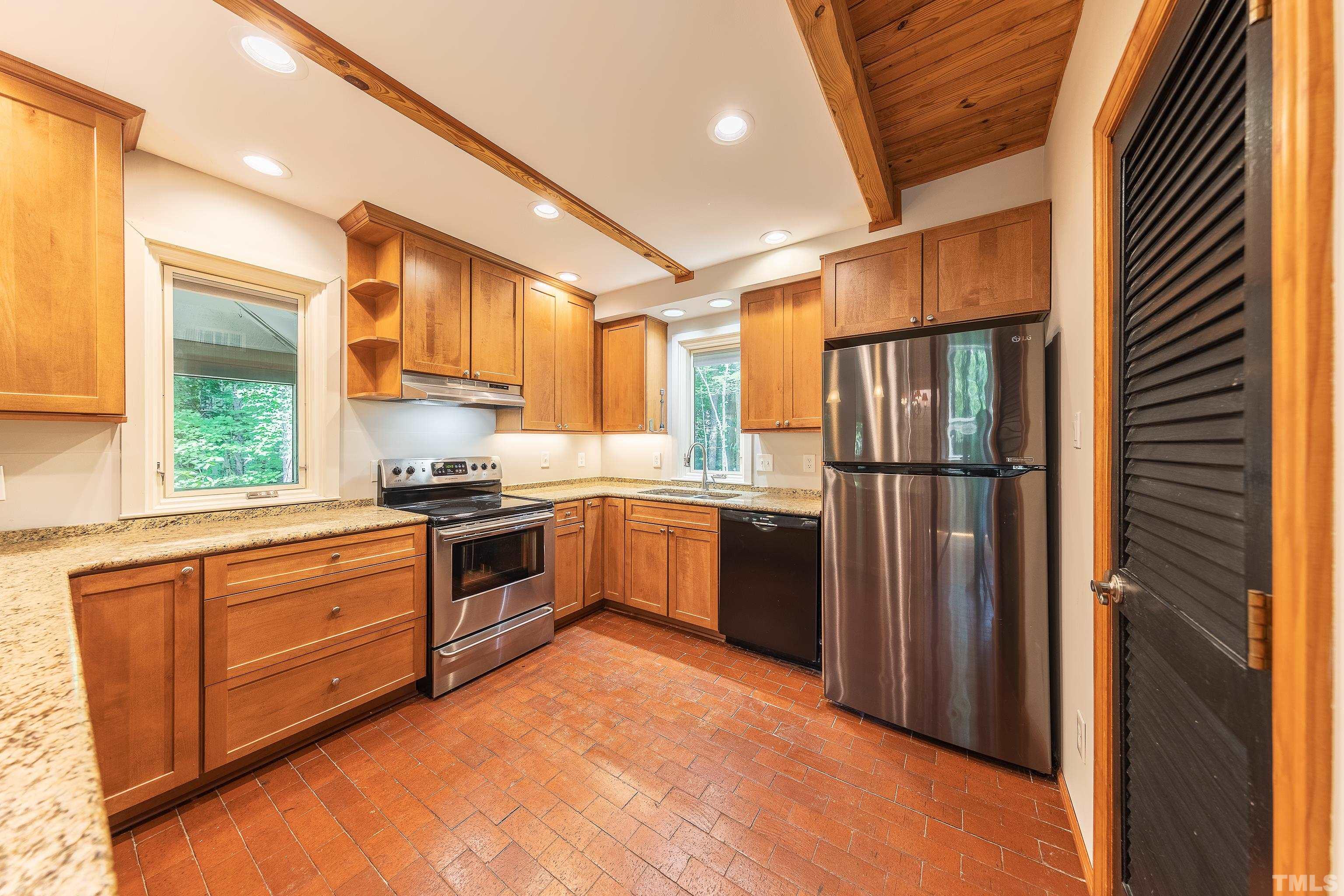 12217 Old Creedmoor Road Raleigh, NC 27613 - Photo 11 of 41 a kitchen with stainless steel appliances granite countertop a refrigerator a sink dishwasher a stove and a dining table with wooden cabinet
