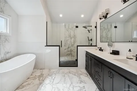 a bathroom with a double vanity sink mirror and bathtub