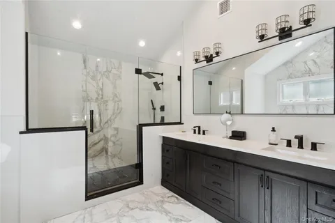 a bathroom with a double vanity sink mirror and shower