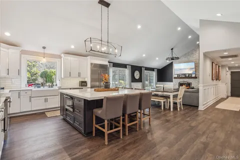 a kitchen with stainless steel appliances granite countertop a table chairs stove and a wooden floor