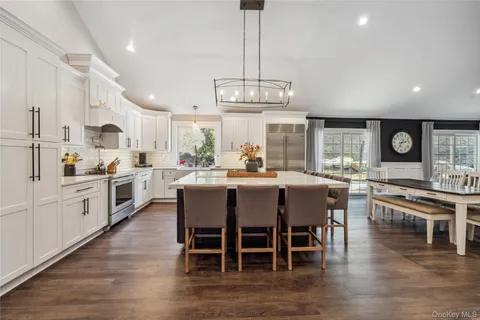 a kitchen with stainless steel appliances a dining table chairs stove and wooden floor