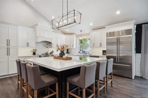 a kitchen with stainless steel appliances a dining table chairs stove and refrigerator