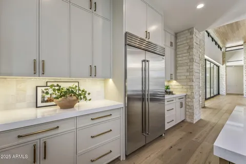 a kitchen with a refrigerator and countertop white cabinets