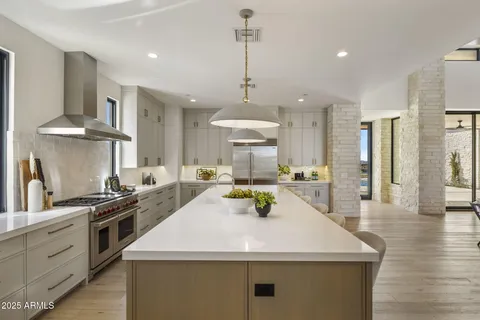 a kitchen with stainless steel appliances granite countertop a sink a stove and a wooden floors