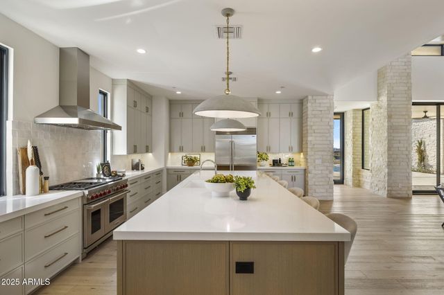 a kitchen with stainless steel appliances granite countertop a sink a stove and a wooden floors