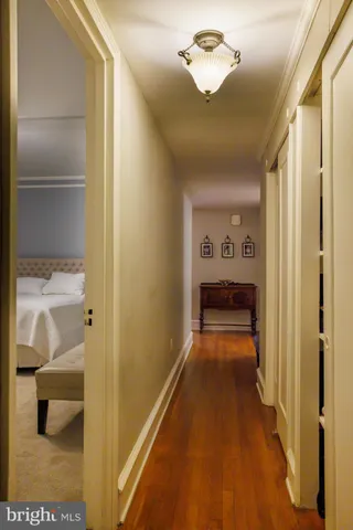 a view of a hallway with wooden floor and a bathroom