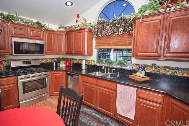 20058 Rancherias Lane Apple Valley, CA 92307 - Photo 32 of 83 a kitchen with stainless steel appliances granite countertop a stove top oven a sink dishwasher and cabinets with wooden floor