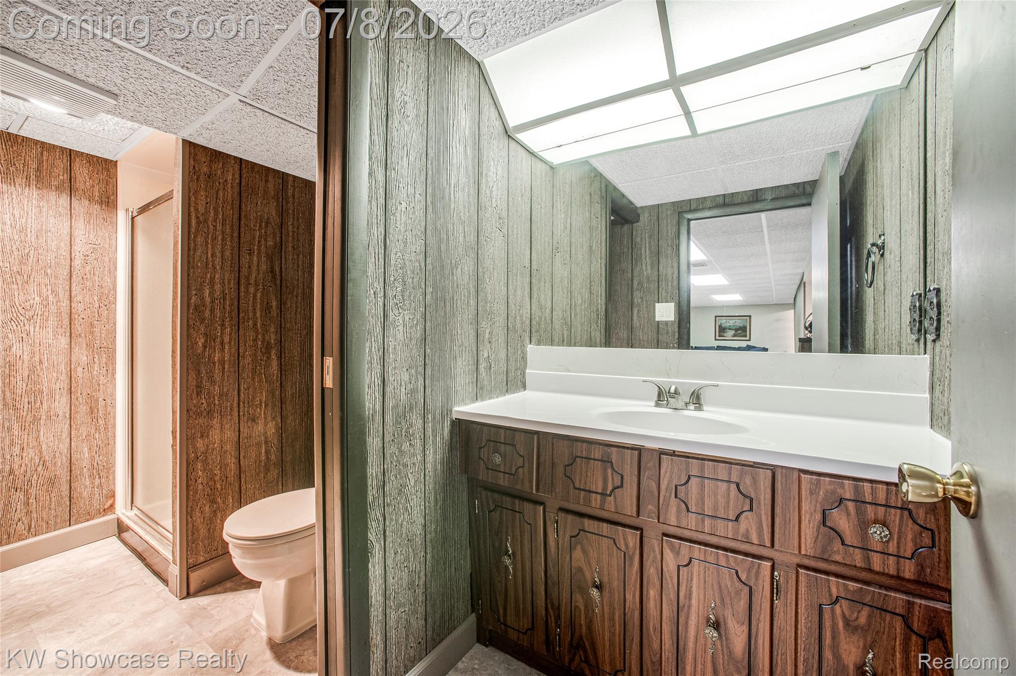 16720 Wayne Road Livonia, MI 48154 - Photo 29 of 29 Bathroom featuring a wood-panel accent wall and a vanity with an integrated sink and mirror
