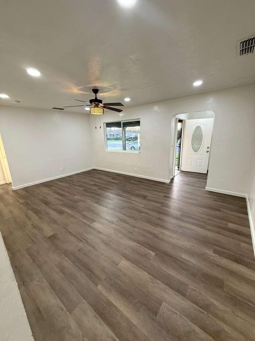 520 Colfax Avenue Modesto, CA 95354 - Photo 4 of 18 an empty room with wooden floor ceiling fan and windows