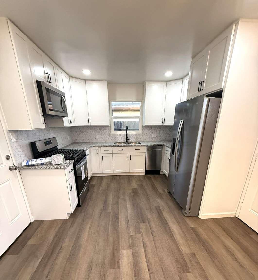 520 Colfax Avenue Modesto, CA 95354 - Photo 6 of 18 a kitchen with stainless steel appliances a refrigerator a sink a stove a microwave and wooden floors