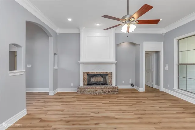 a view of a livingroom with a fireplace a ceiling fan and wooden floor
