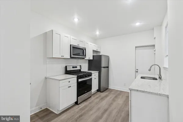 a kitchen with a sink a stove a microwave refrigerator and cabinets