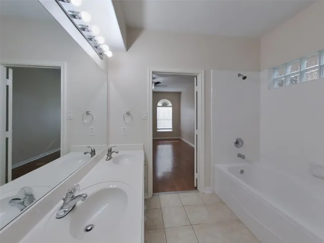 a bathroom with a tub sink shower and mirror