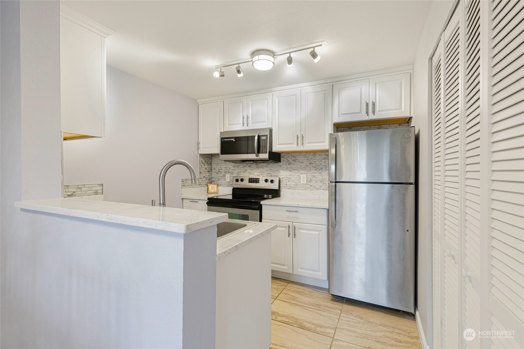 11002 Southeast Petrovitsky Road, Unit F202 Renton, WA 98055 - Photo 7 of 20 a kitchen with a refrigerator a sink a stove a microwave and cabinets