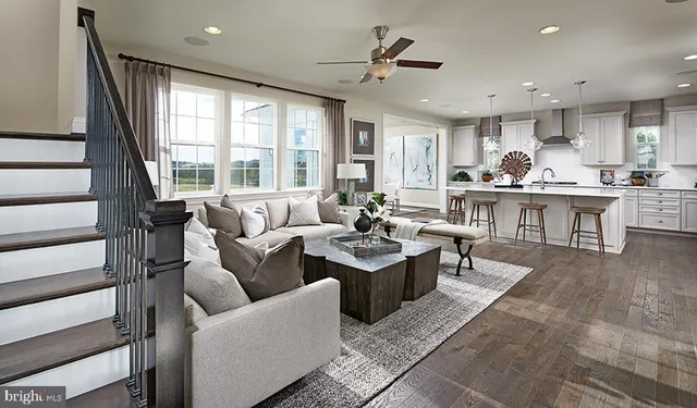 a living room with furniture kitchen area and a large window